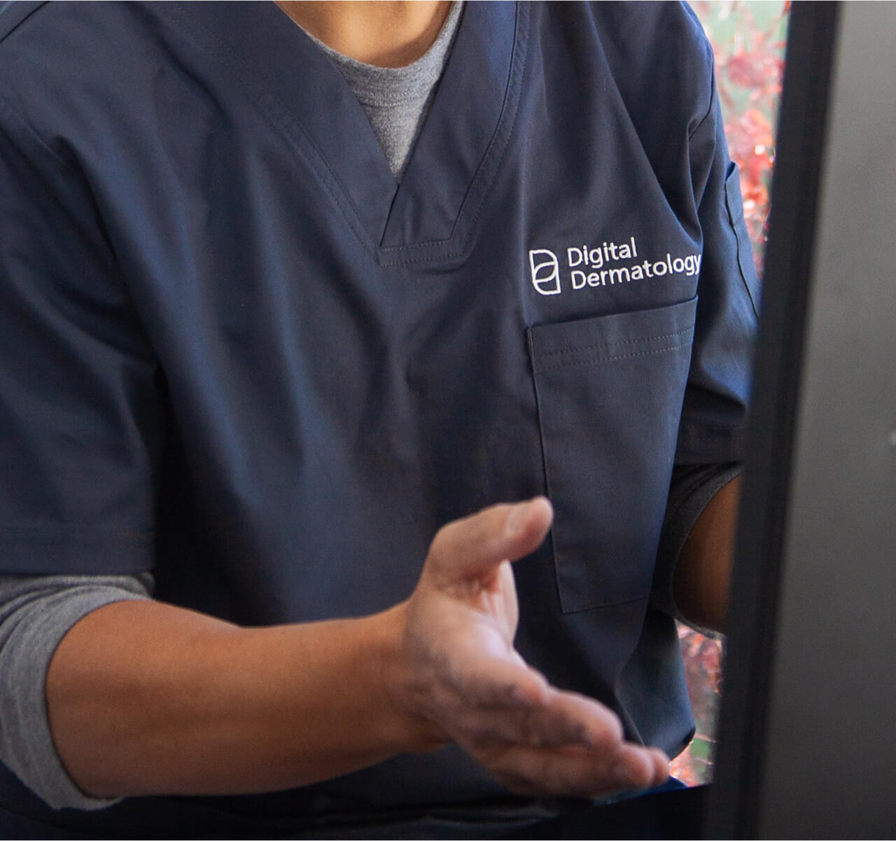 Close-up of Dermatologist with Digital Dermatology logo embroidered onto their scrub speaking to a patient