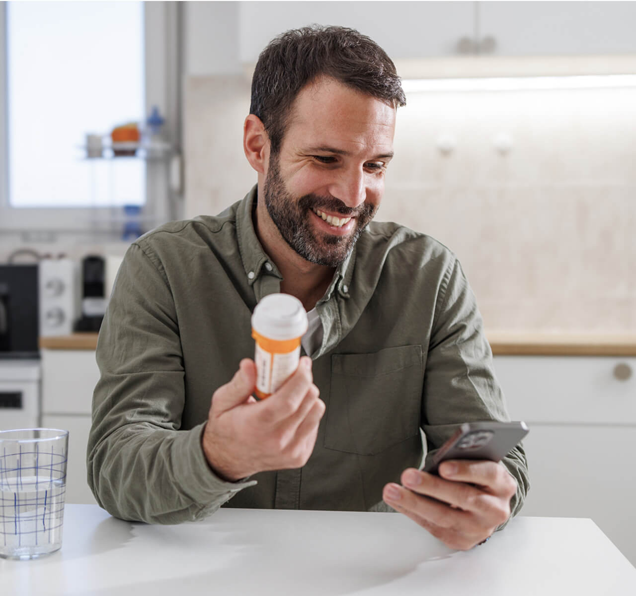 Patient holding a medication bottle while looking through their phone